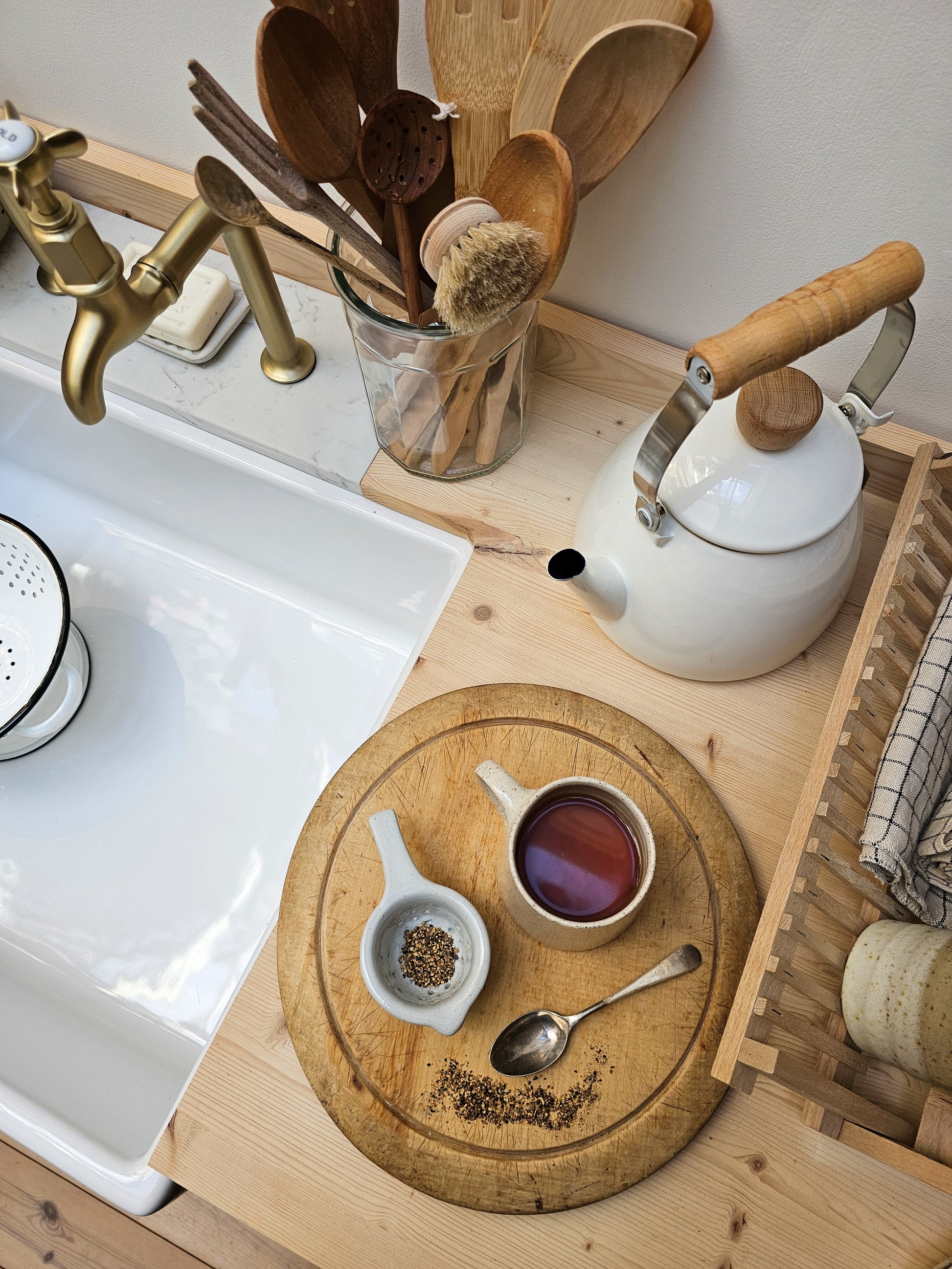 Kitchen counter with a teapot, wooden utensils, and a cutting board with tea.