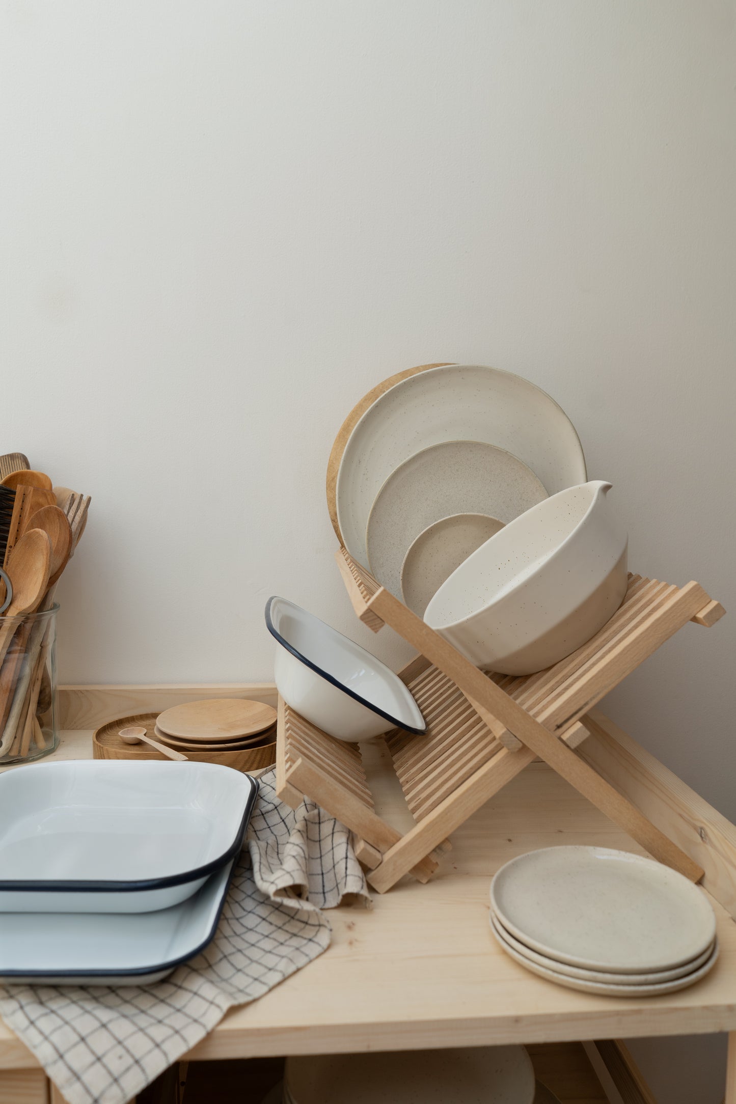 Dishes on a wooden rack and table against a white wall.