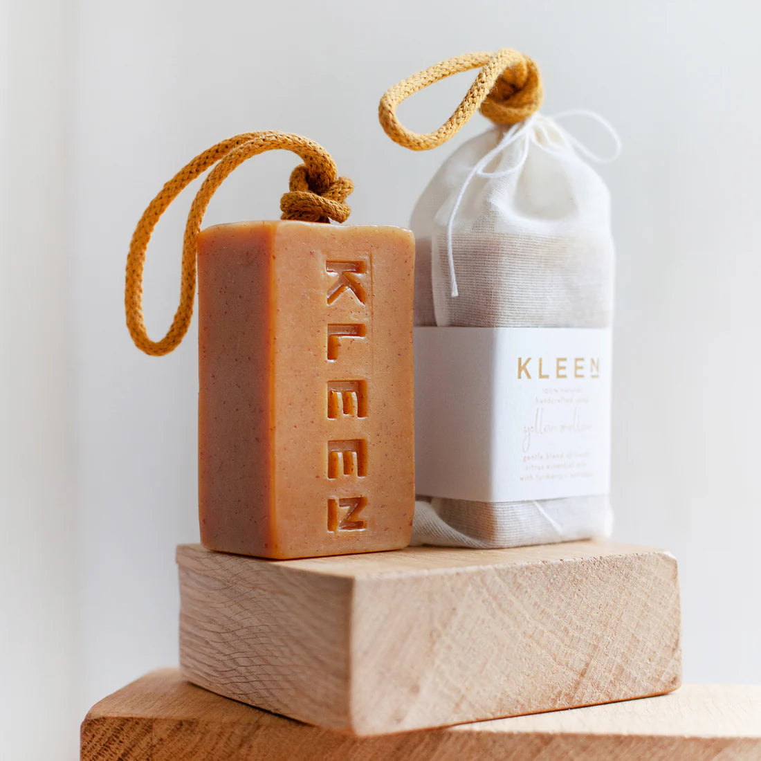 Kleen bar of soap and white drawstring bag on a wooden block with a white background