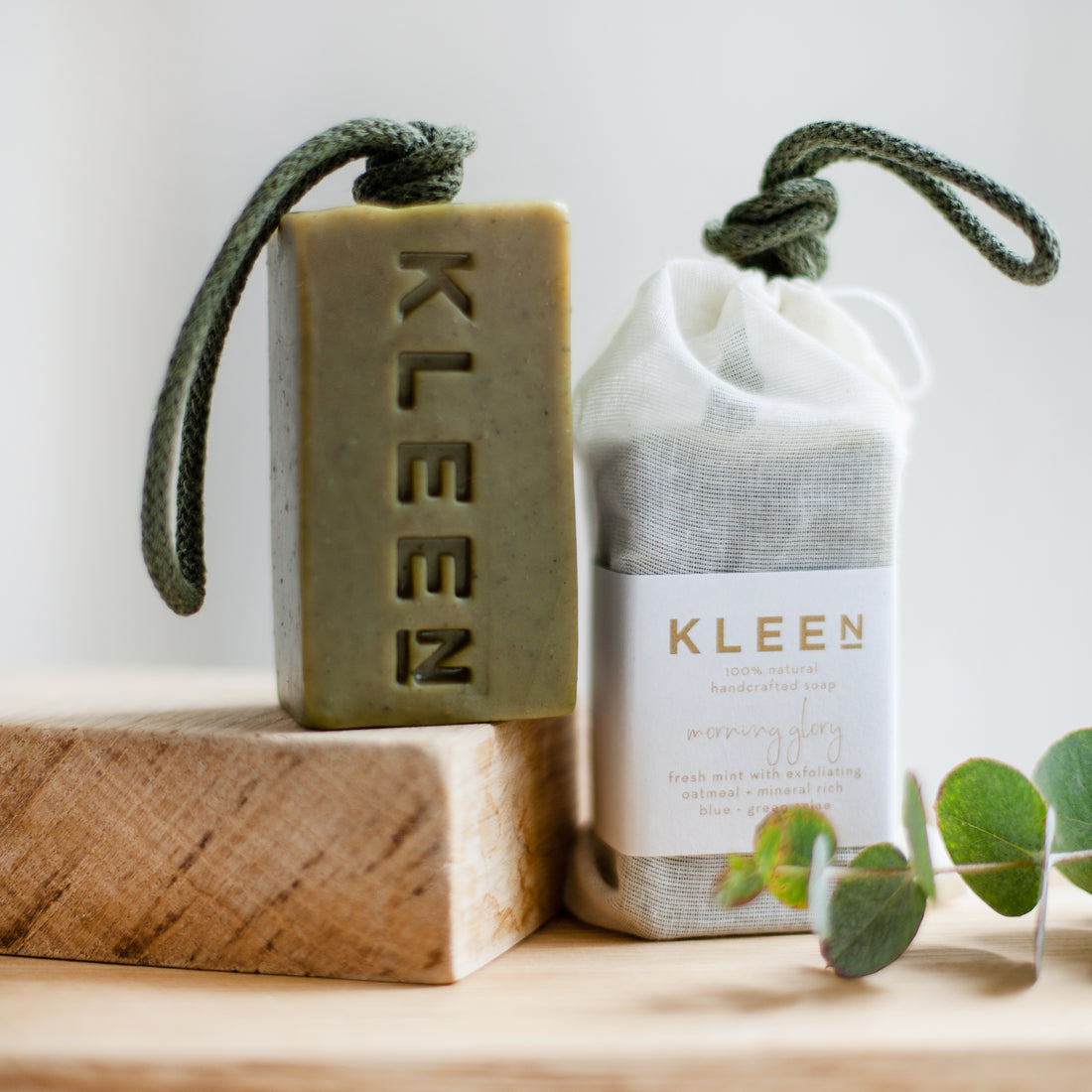 Bar of soap and cloth pouch with 'KLEEN' branding on a wooden surface.