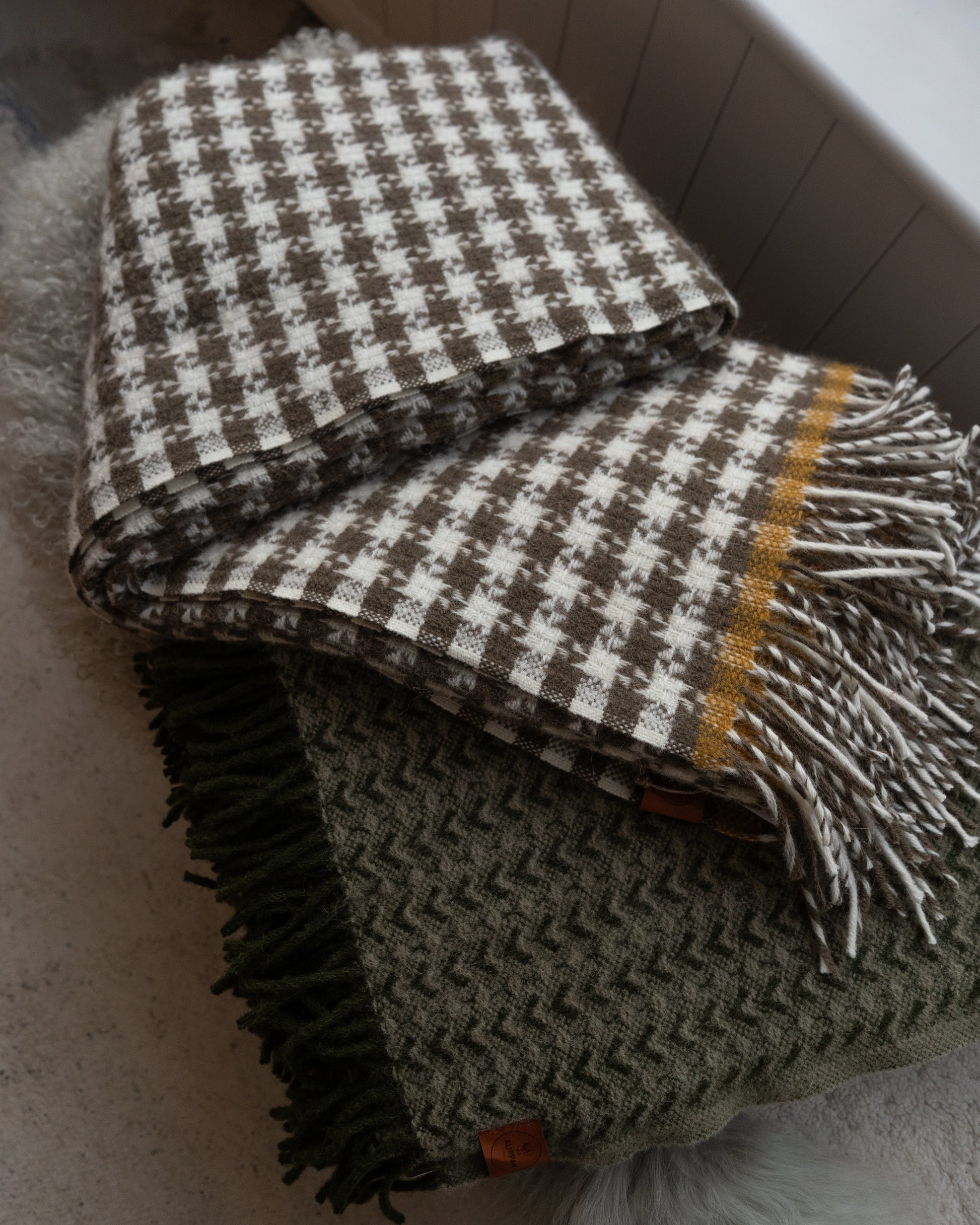 Stack of checkered blankets with fringes on a neutral background