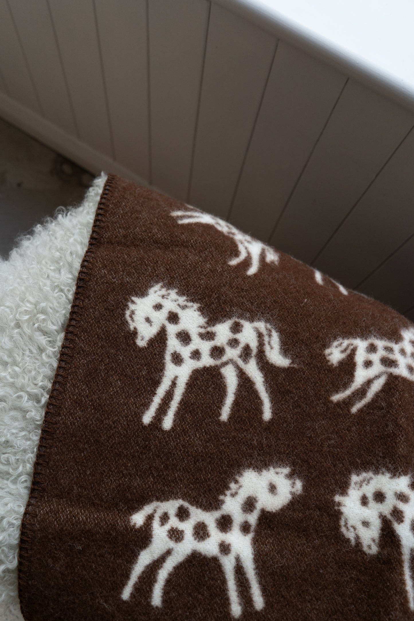 Brown blanket with white horse patterns.