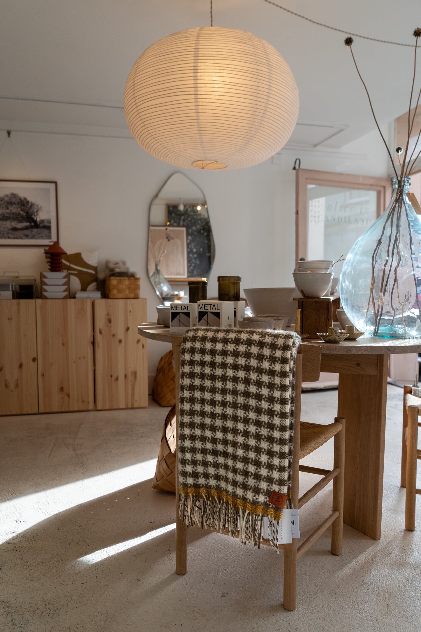 Dining room with wooden table, chair with checkered blanket, and pendant light.