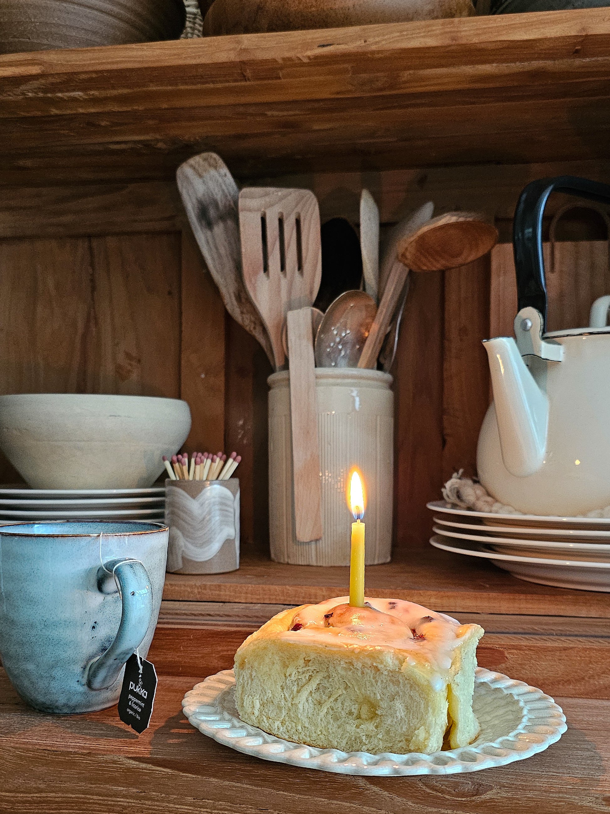 A lit mini beeswax candle placed in a cake within a kitchen setting. 