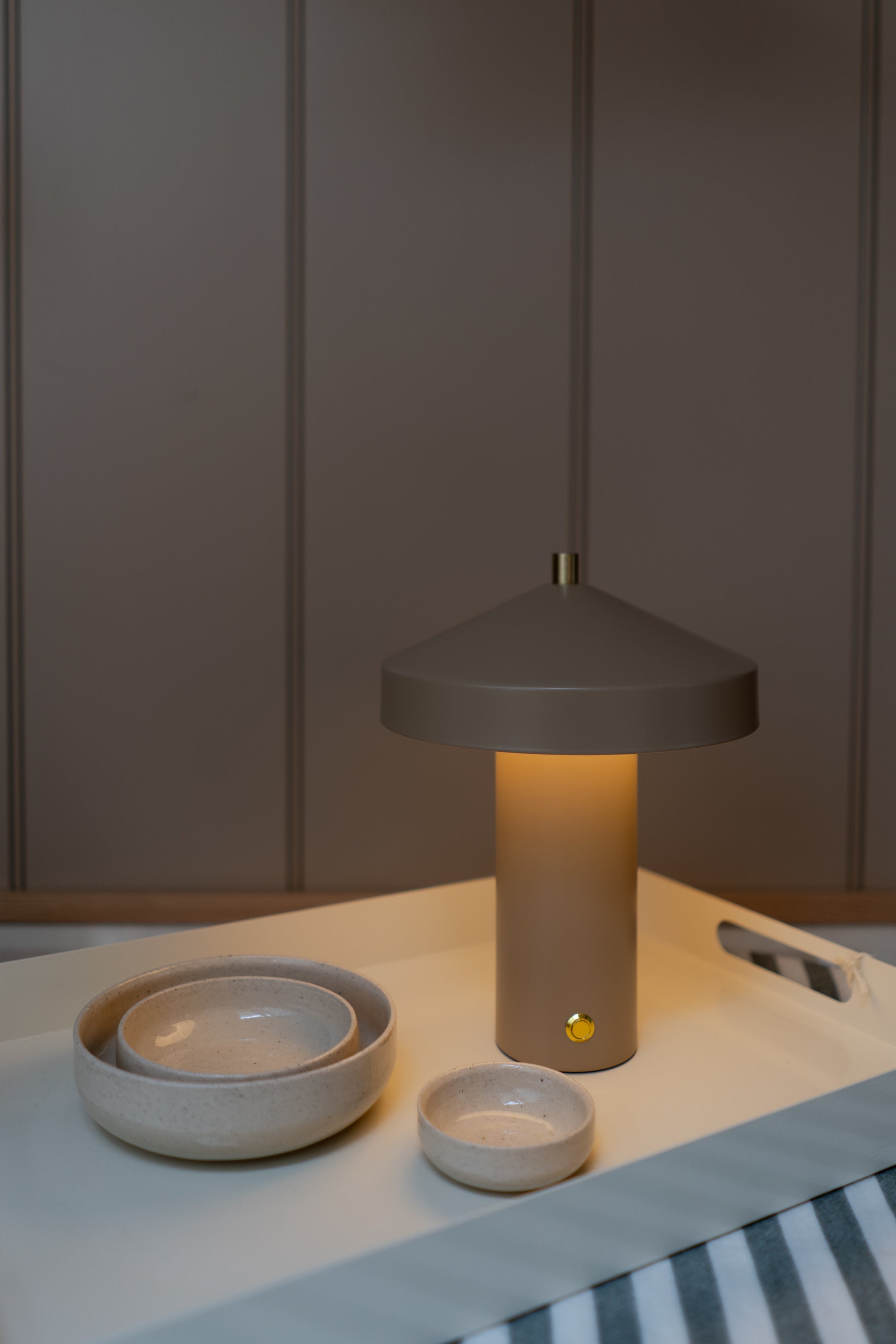 Table lamp on a surface with bowls and a striped fabric background
