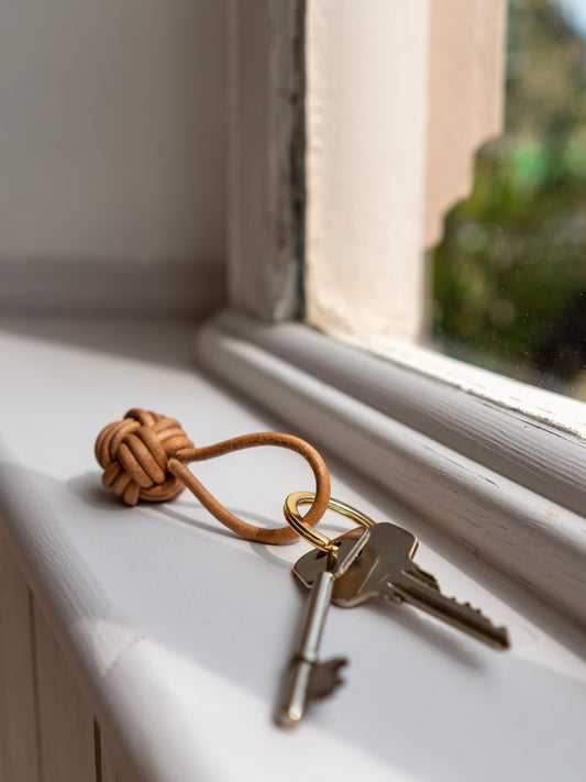 Keys on a leather knot keychain on a windowsill with natural light