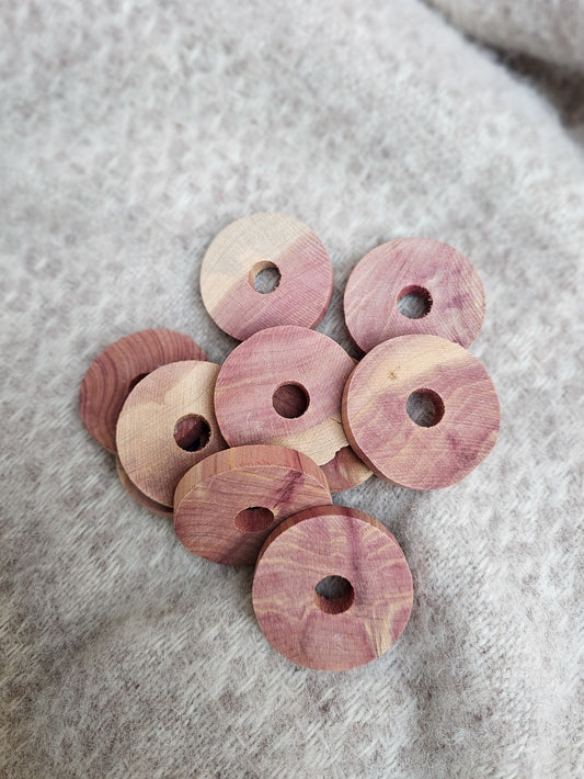 A scattering of red cedarwood moth discs on a grey wool blanket.