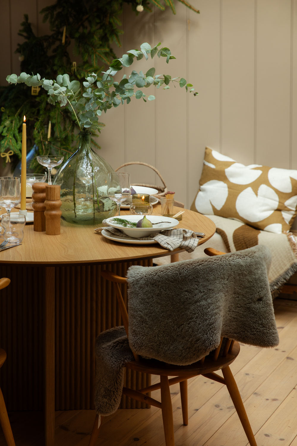 Dining room with a table setting and a taupe sheepskin rug draped over a wooden chair.
