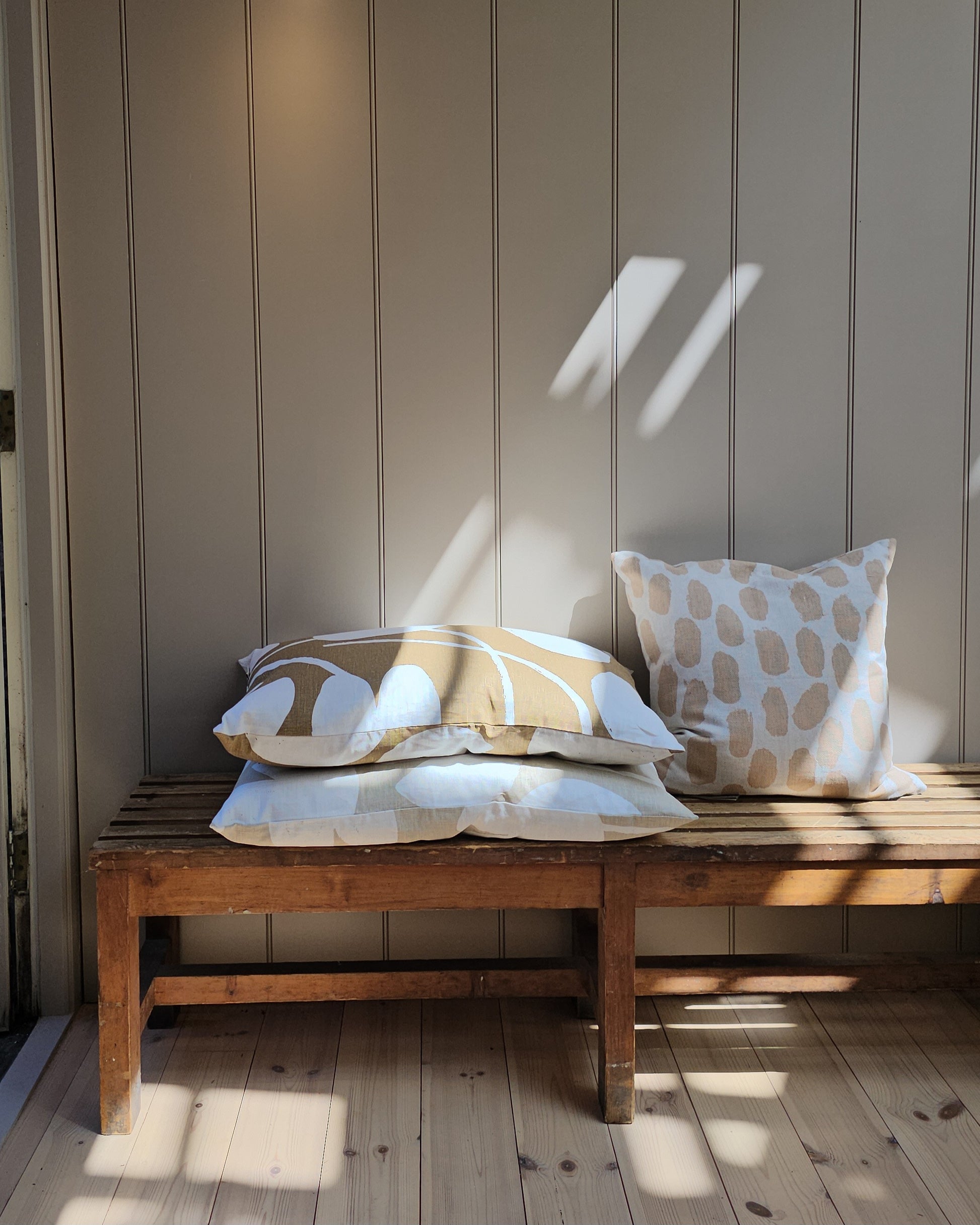 Vintage wooden bench with patterned cushions against a paneled wall