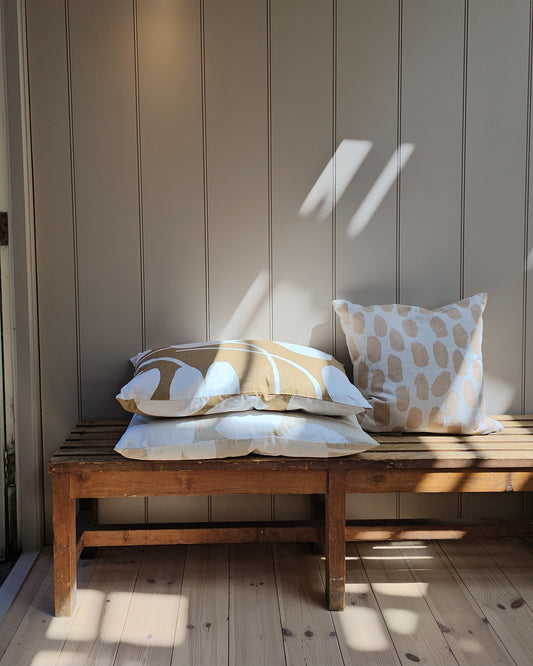 Vintage wooden bench with patterned cushions against a paneled wall