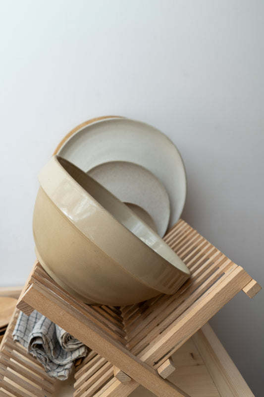 Beige ceramic bowl on a wooden stand against a light gray background