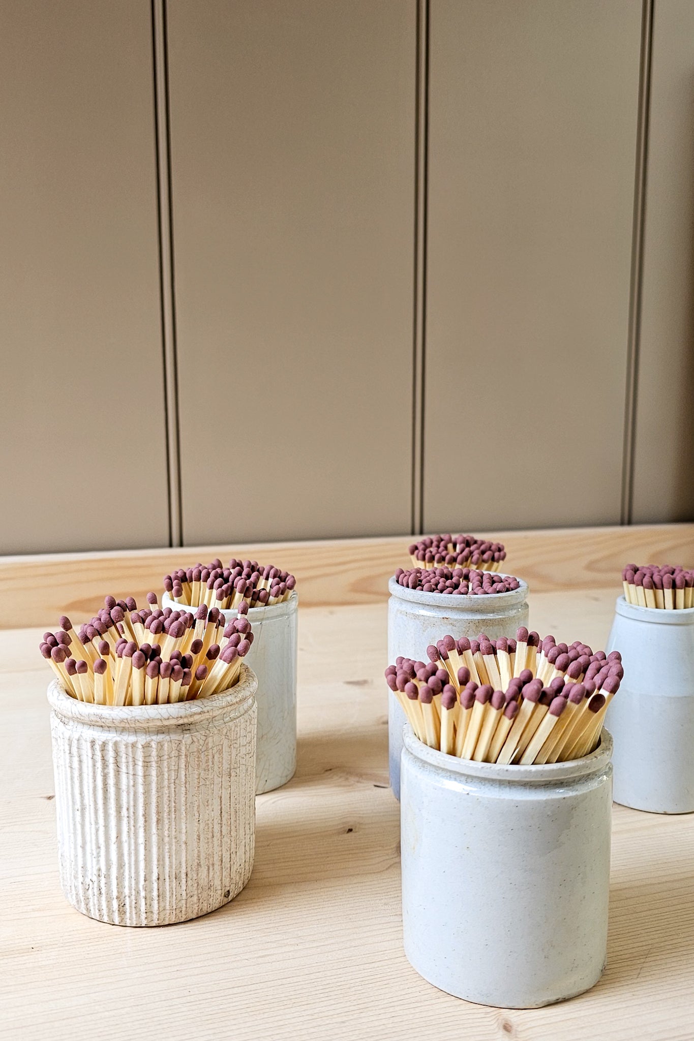Set of matchboxes with matches in small ceramic containers on a wooden surface.