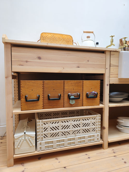 Wooden storage unit with shelves and baskets in a kitchen setting