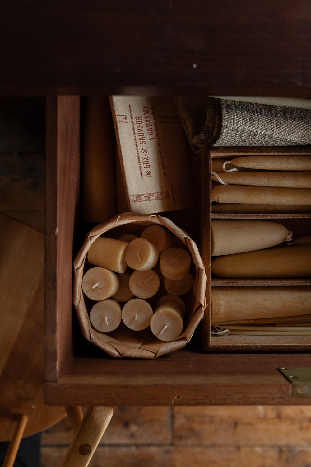 Wooden box with candles and rolled-up papers on a wooden surface