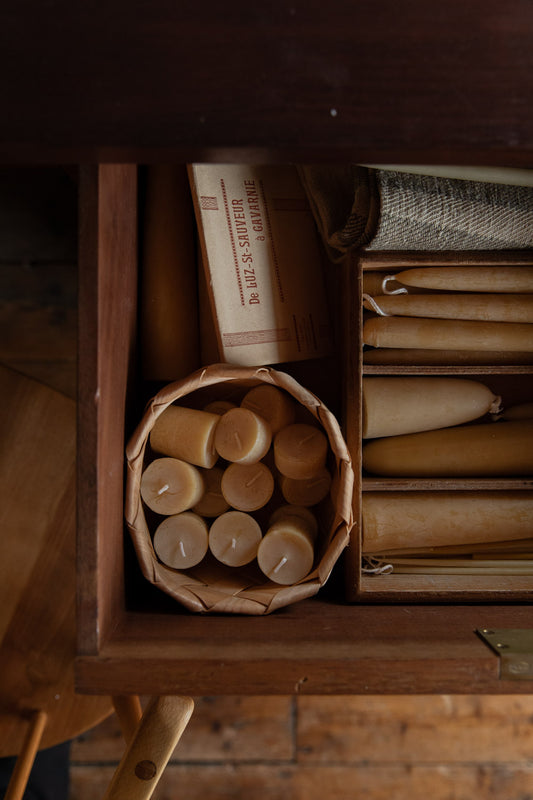 Wooden box with candles and rolled-up papers on a wooden surface