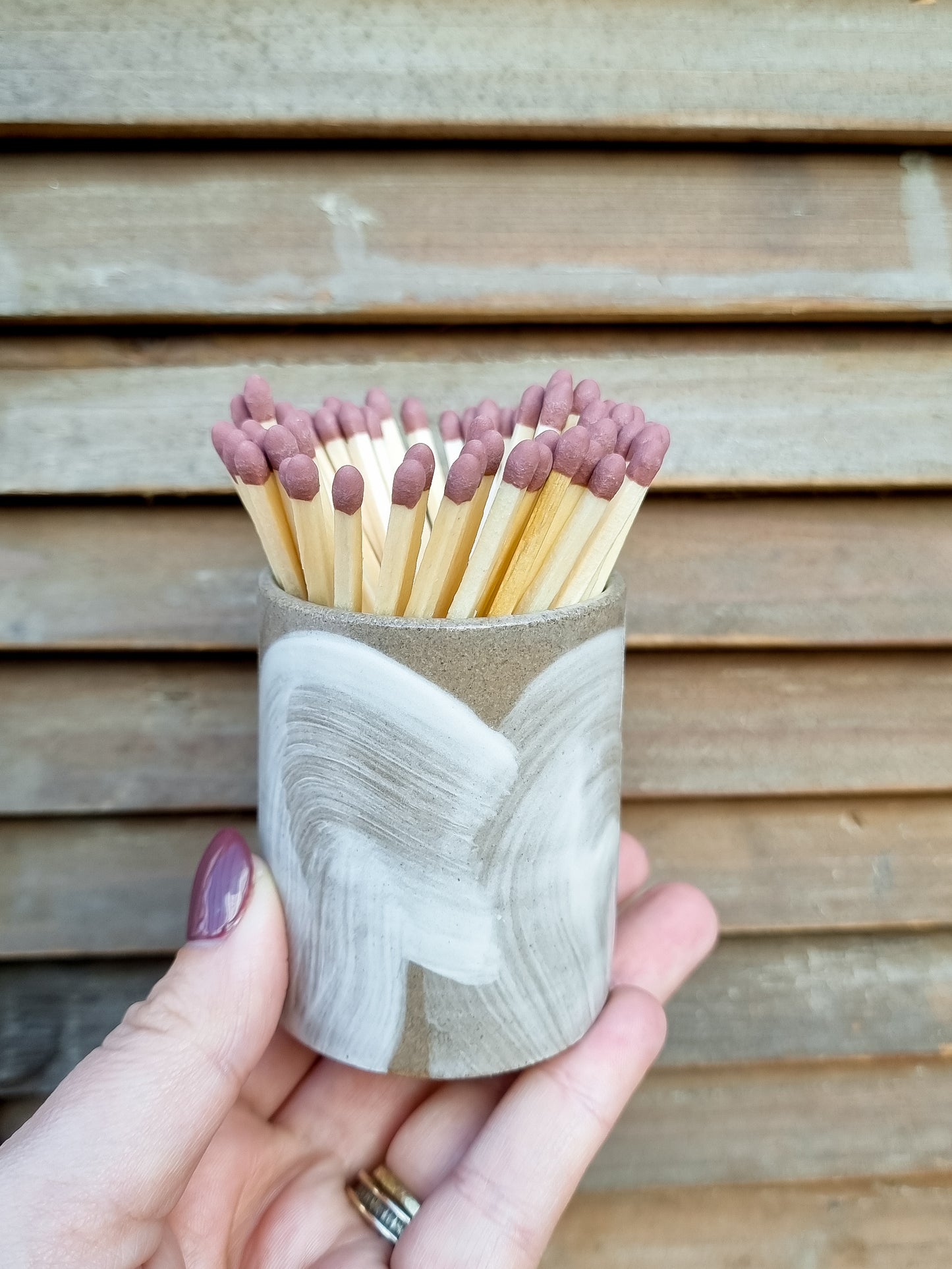 Close-up of a handmade Bel Holland brushstroke stoneware match pot held in hand, filled with extra long matches