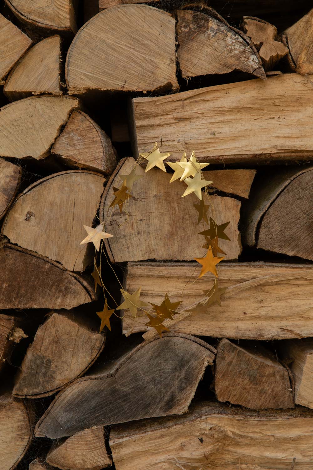 Brass star garland looped into a ring against stacked firewood