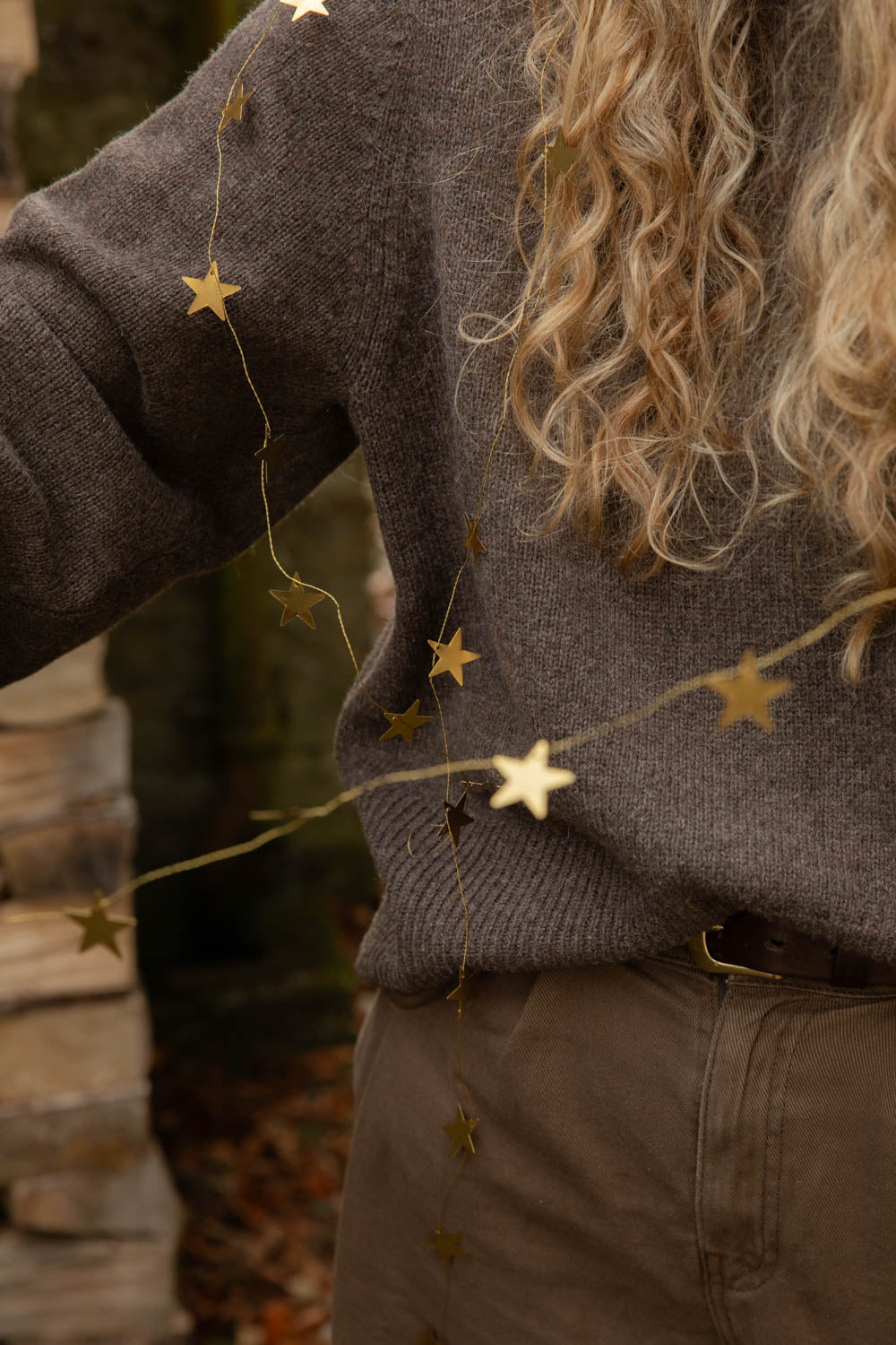 Brass star garland trailing over a woman's brown wool jumper