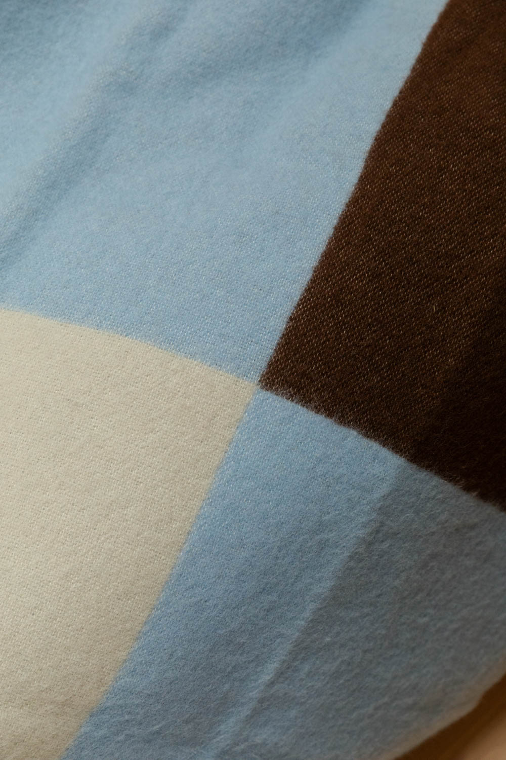 Close-up of Brita Sweden Pop lambswool blanket in blue, brown and cream large block check showing soft brushed texture detail.