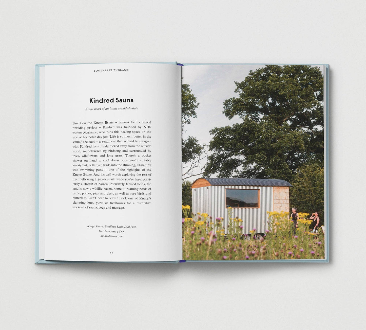 Open book showing a photograph of a small wooden sauna in a field with trees and flowers.