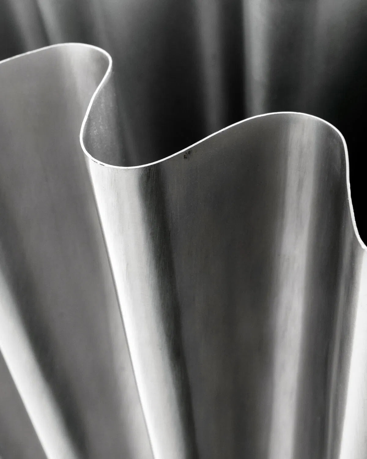 Close up shot of the curves on the lip of a large brushed silver Flood vase.