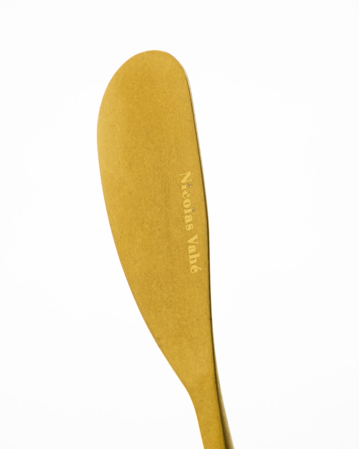 Close-up of an antique gold butter knife blade engraved Nicolas Vahé