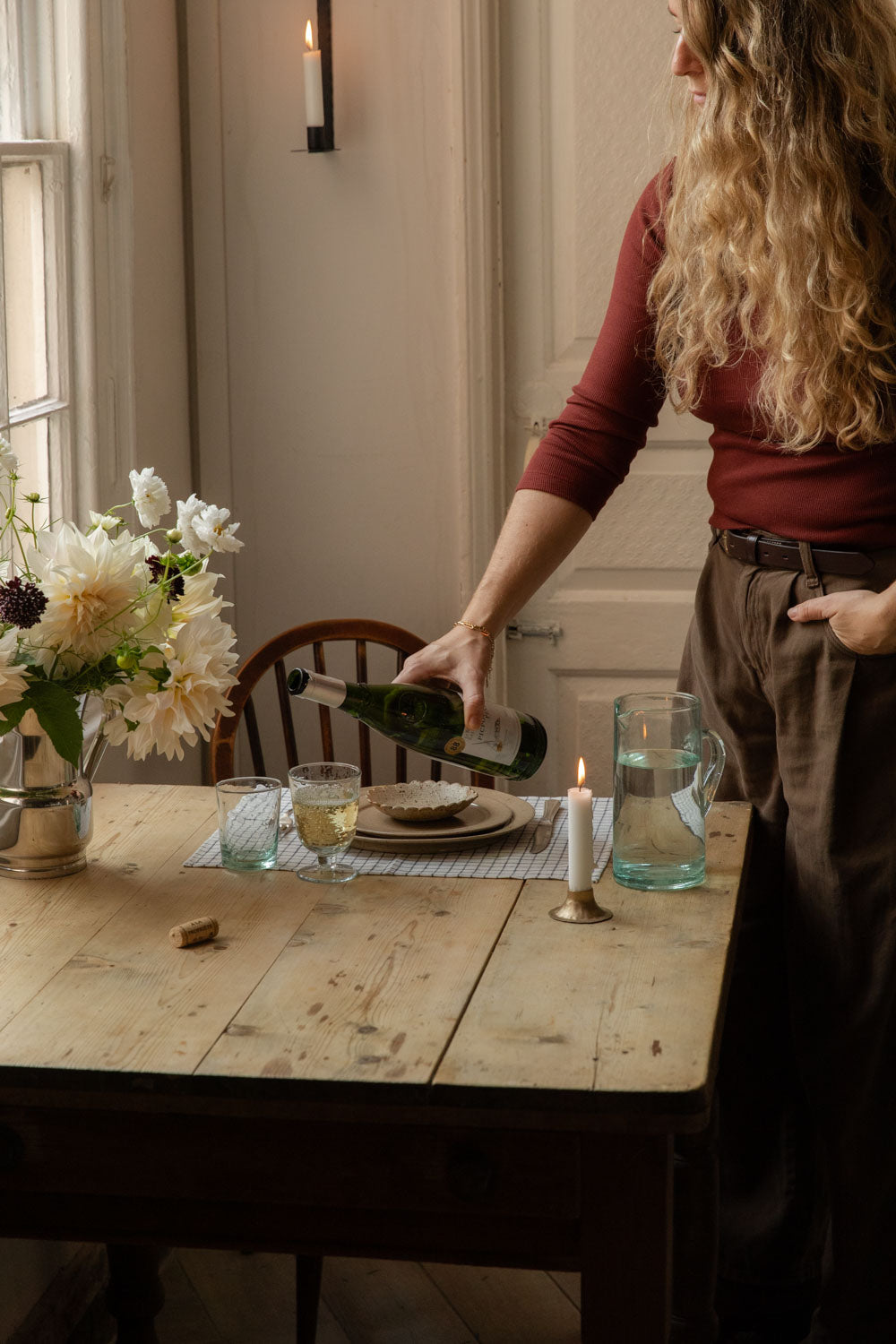 Pouring white wine at a candlelit table set with speckled plates and glassware