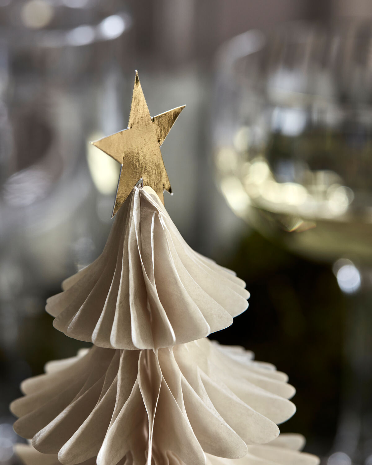 Close-up of a handmade ivory paper Christmas tree with a gold star topper