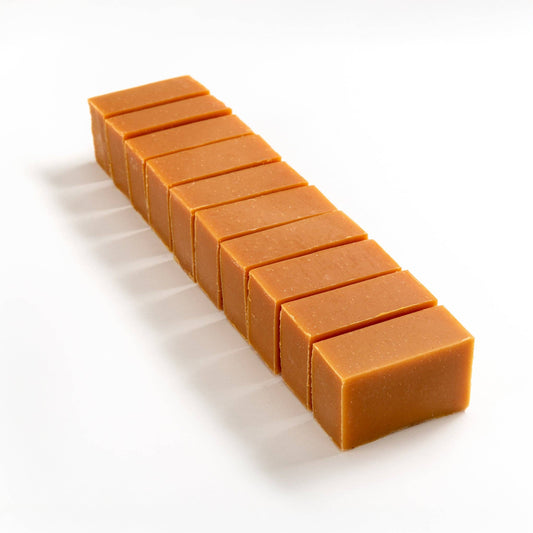 Row of citrus and turmeric soap brick bar cut into smaller pieces on a white background