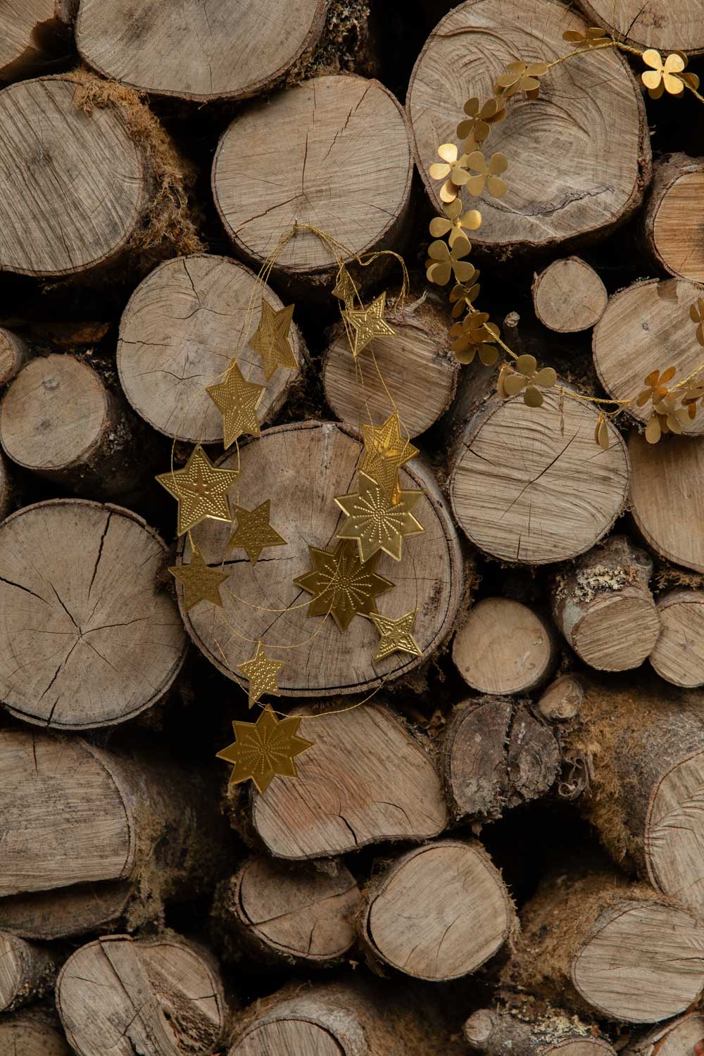 Embossed gold star garland draped across a stack of split logs