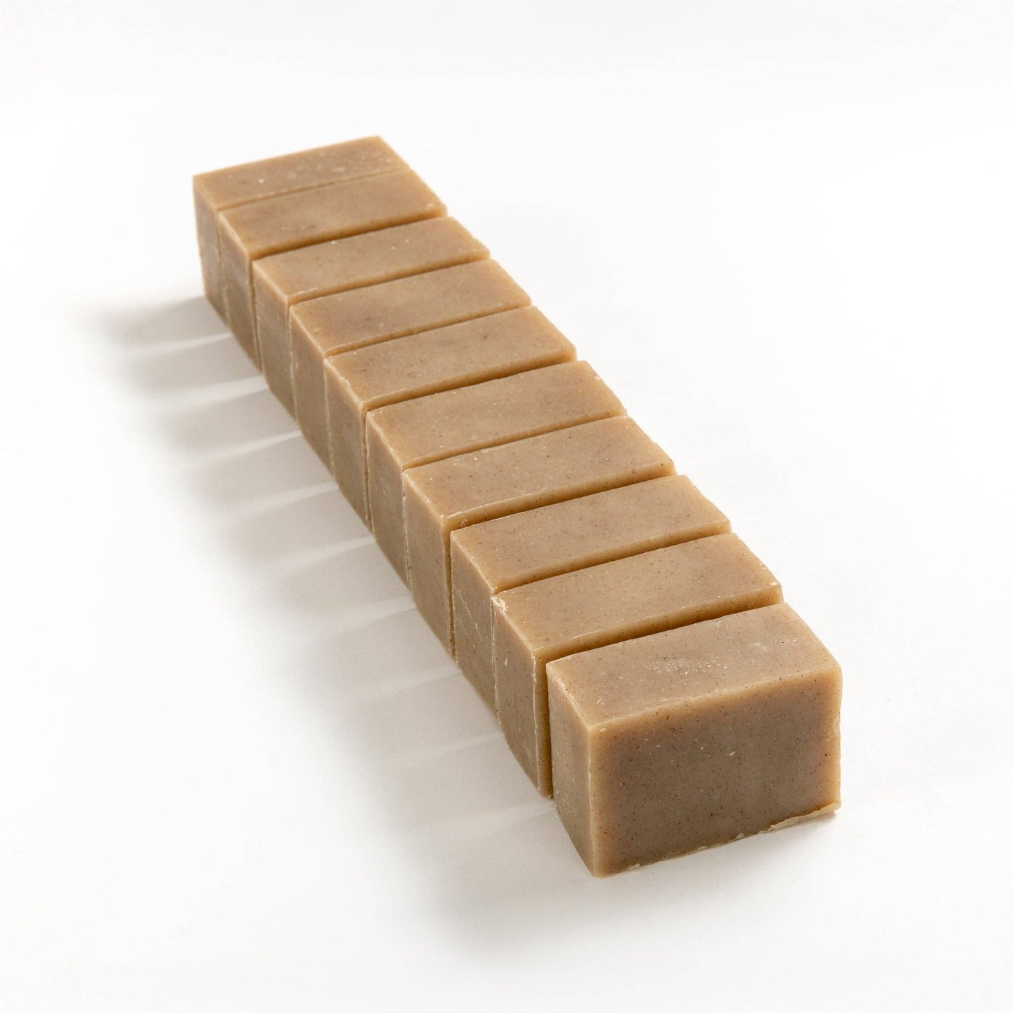 Row of English lavender soap brick cut into smaller pieces on a white background.