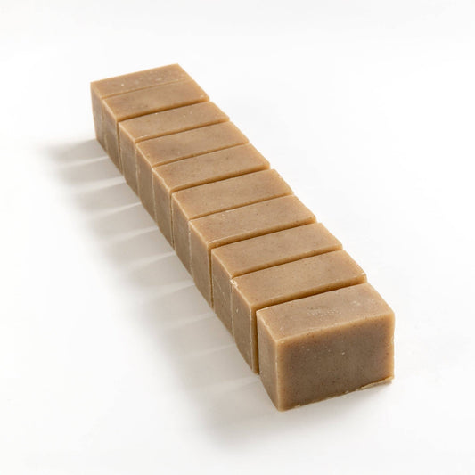 Row of English lavender soap brick cut into smaller pieces on a white background.