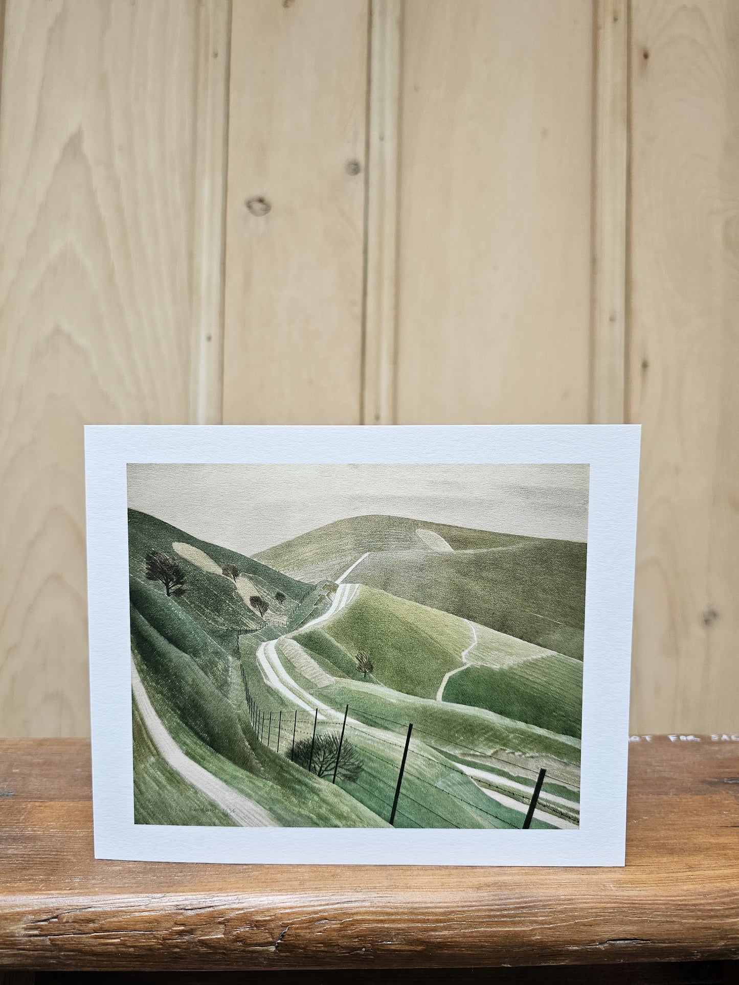 Greeting card reproducing Eric Ravilious's 1935 watercolour Chalk Paths, showing winding paths across rolling chalk downland with telegraph poles and scattered trees