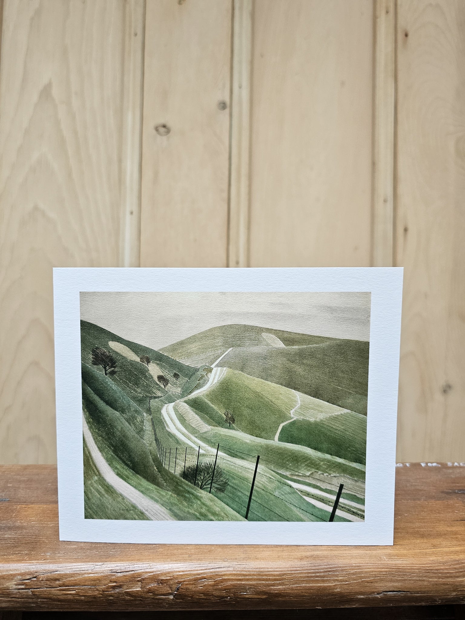 Greeting card reproducing Eric Ravilious's 1935 watercolour Chalk Paths, showing winding paths across rolling chalk downland with telegraph poles and scattered trees