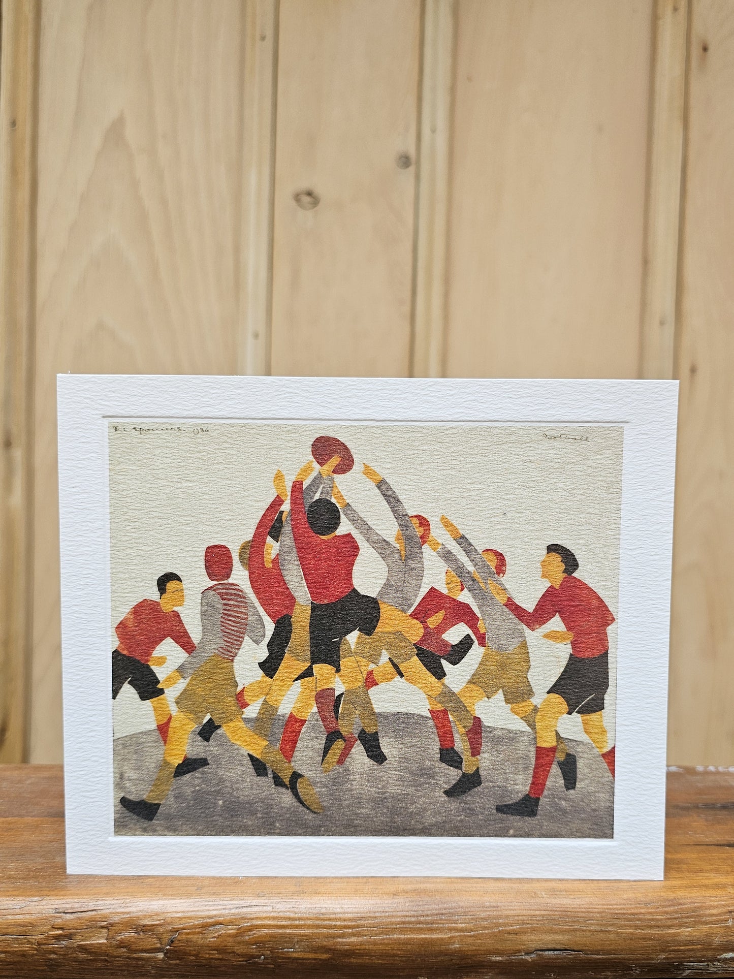 Greeting card reproducing Ethel Spowers's 1936 linocut Football, showing a dynamic crowd of players jumping for the ball in bold red, gold and black