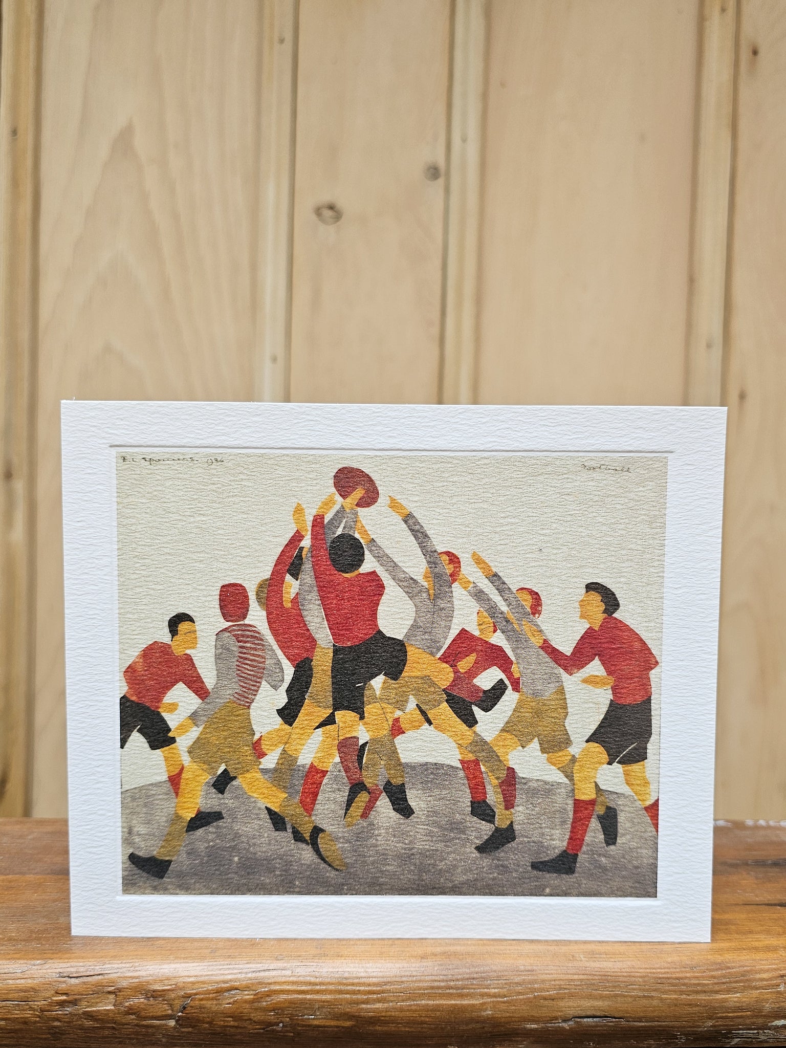 Greeting card reproducing Ethel Spowers's 1936 linocut Football, showing a dynamic crowd of players jumping for the ball in bold red, gold and black