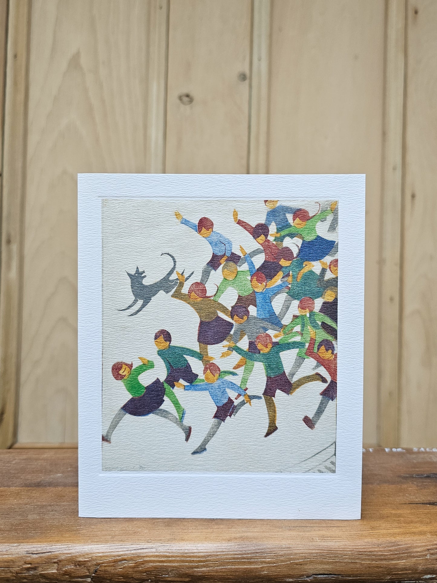 Greeting card reproducing Ethel Spowers's linocut School is Out, showing a joyful crowd of children running and leaping with arms raised, chased by a leaping cat