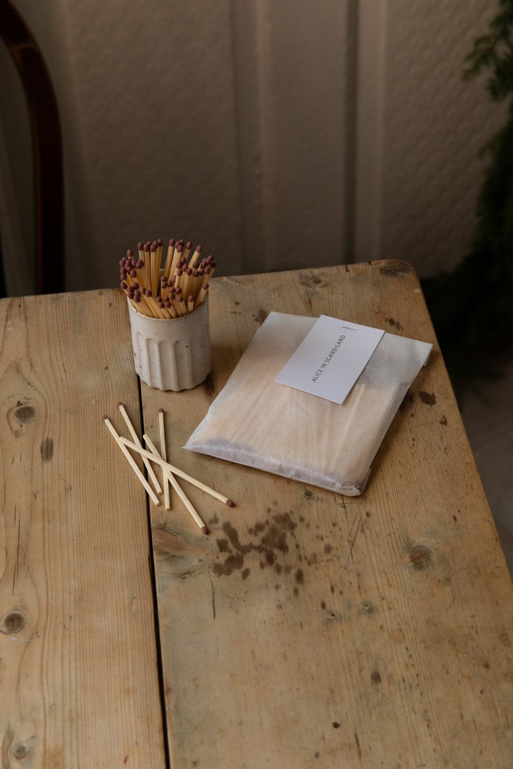 Glassine pack of extra long matches beside a fluted stoneware match pot filled with matches