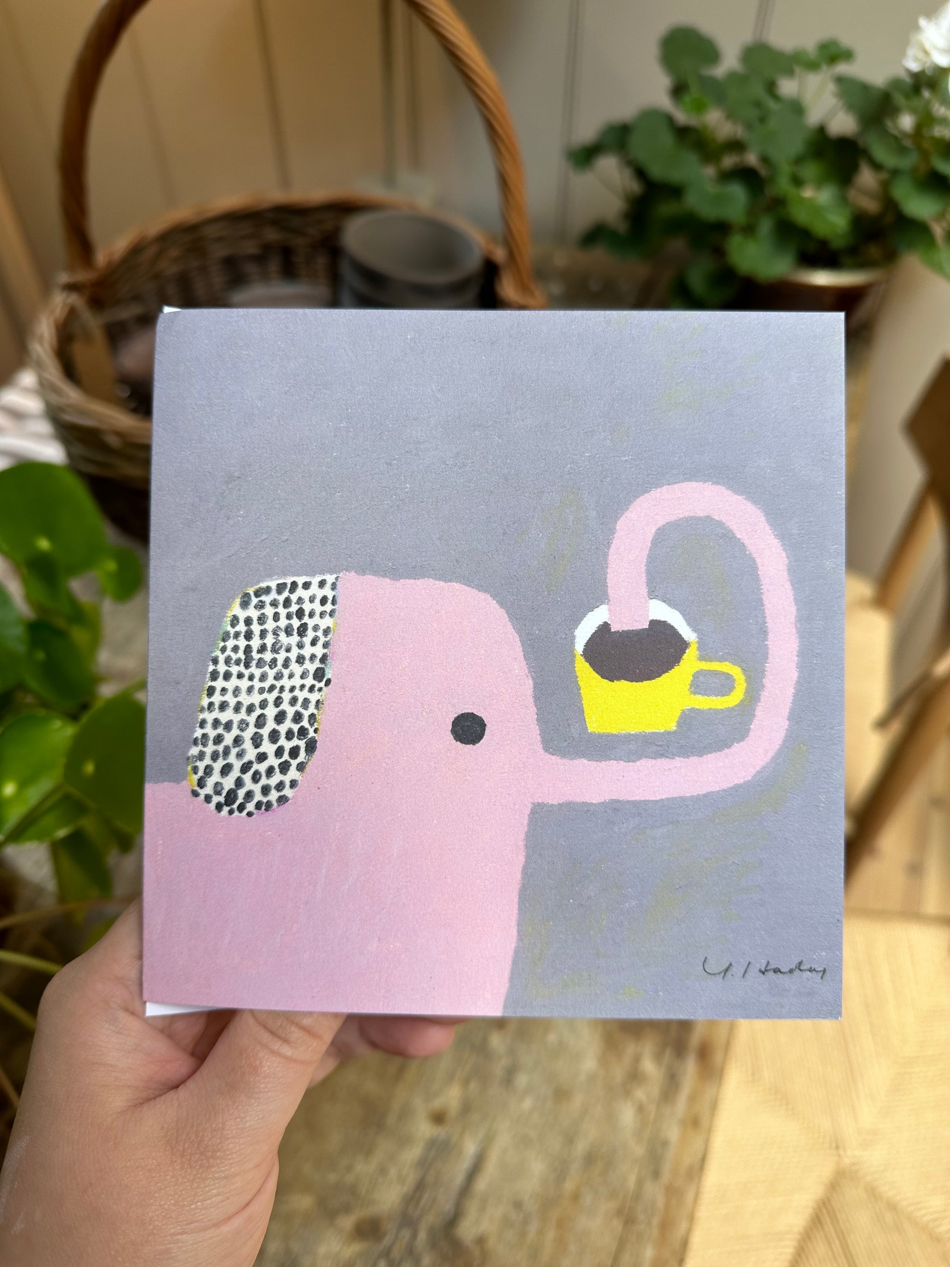 A person holding greeting card with a cartoon drawing of an elephant on it.
