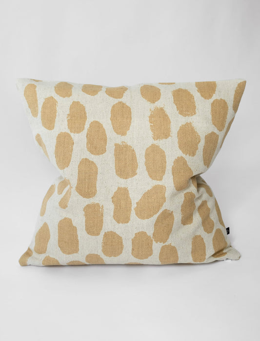 A square-shaped cushion with a beige background and a pattern of sand coloured dots.