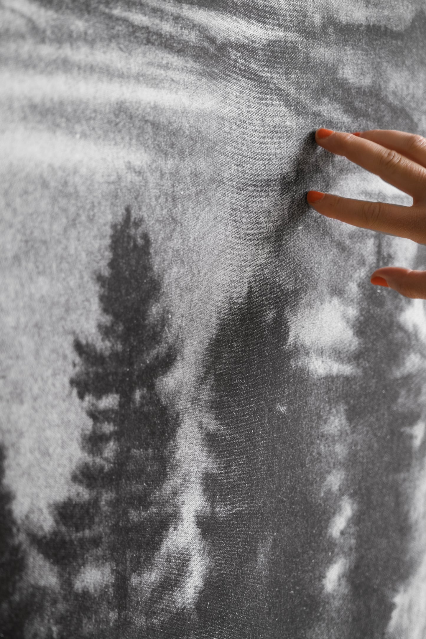 Hand touching a textured surface with a blurred natural scene in the background.