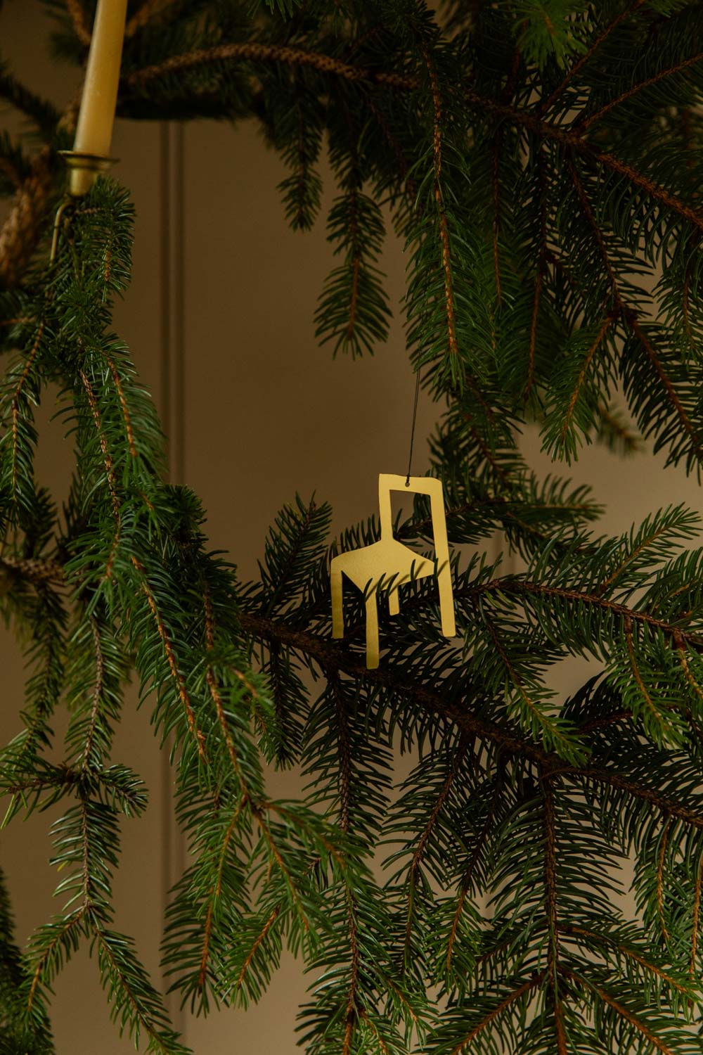 Small gold coloured metal chair ornament on a Christmas tree branch.