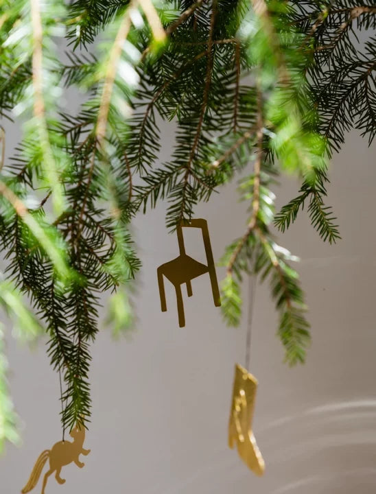Small gold coloured metal chair ornament on a Christmas tree branch.