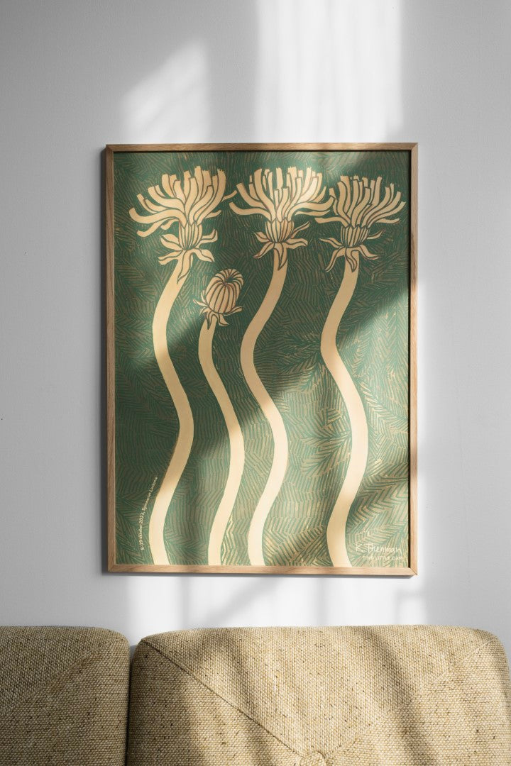 A framed poster featuring abstract floral designs in gold/beige colour on a green background, hanging on a wall above a sofa.