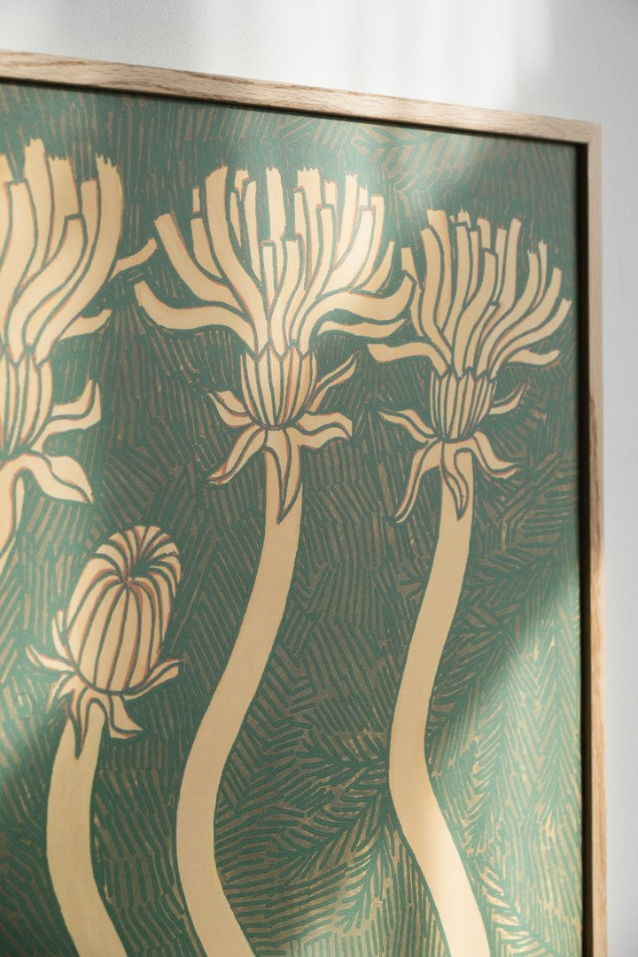 Close up of a  framed poster featuring abstract floral designs in gold/beige colour on a green background, hanging on a white wall.