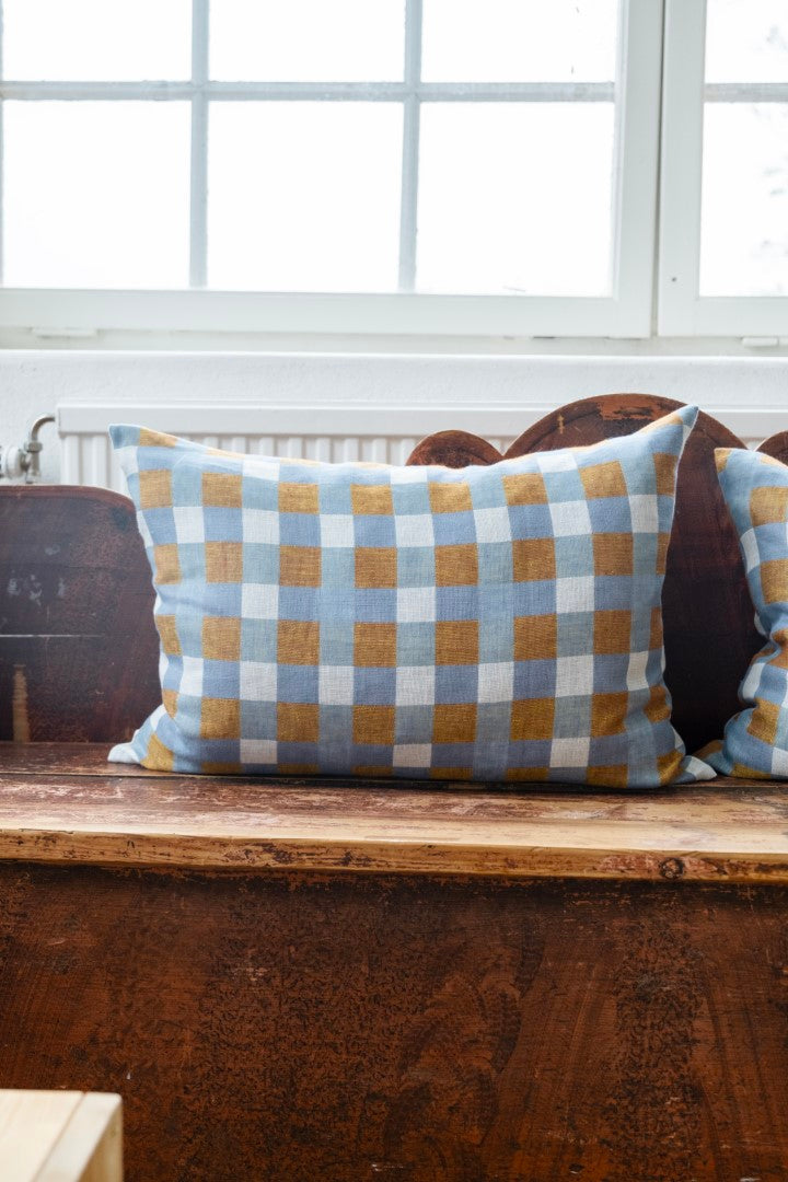 A rectangular linen cushion with a geometric pattern, displayed on a wooden surface.