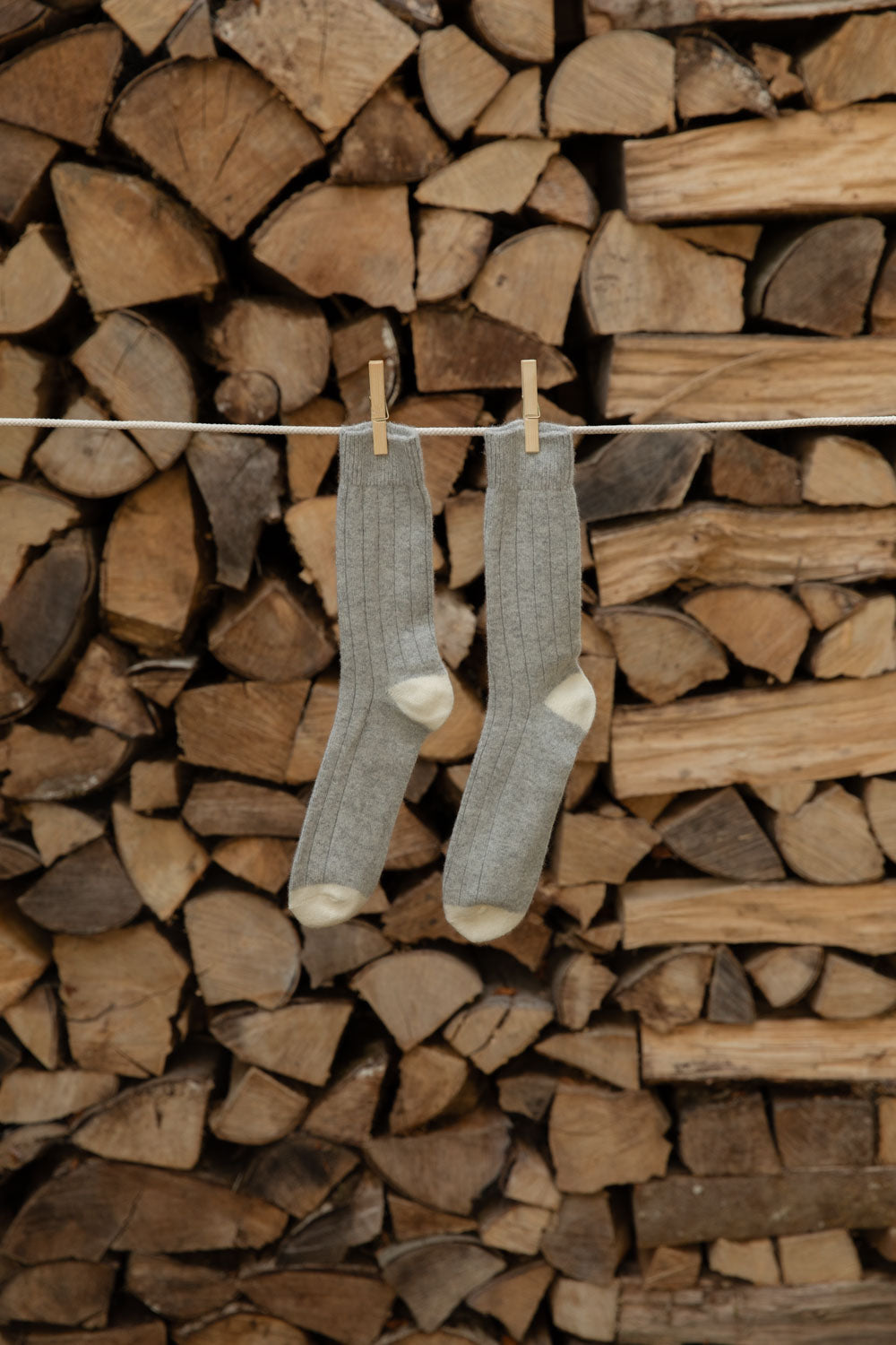Le Bon Shoppe Classic Cashmere Socks in grey melange with cream heels and toes on a line against logs