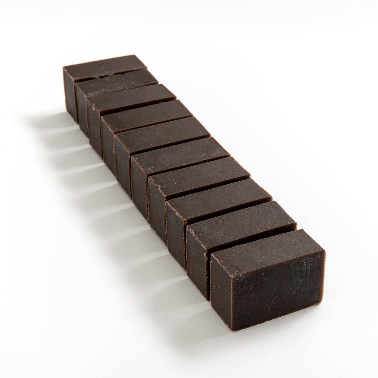 Row of hemp and walnut soap brick cut into smaller pieces on a white background
