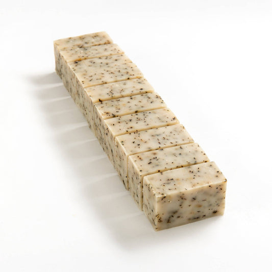 Row of herbal mint soap brick cut into smaller pieces on a white background.