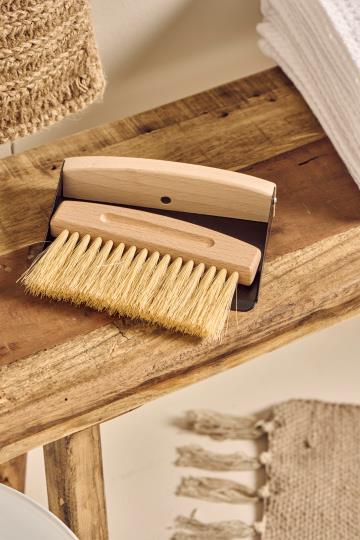 Wooden brush and metal pan on a wooden surface